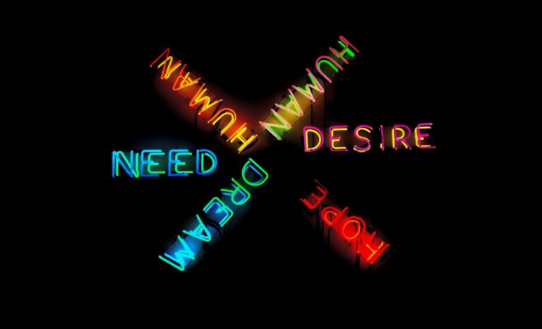 Neon lights reading "human," "desire," "hope," "dream," "need"