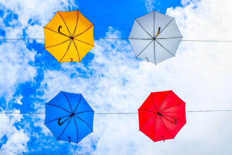 colorful umbrellas against a bright blue sky, from below