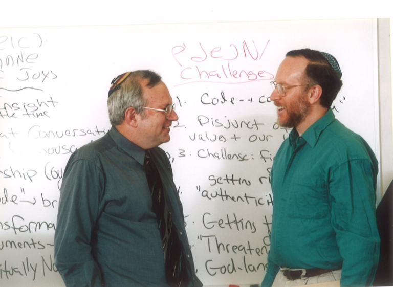 Rabbis Jeffrey Schein and Brian Nevins-Goldman in front of a white board covered with writing