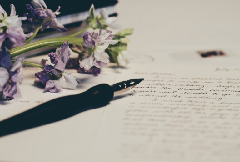 fountain pen and flowers on top of handwritten letter