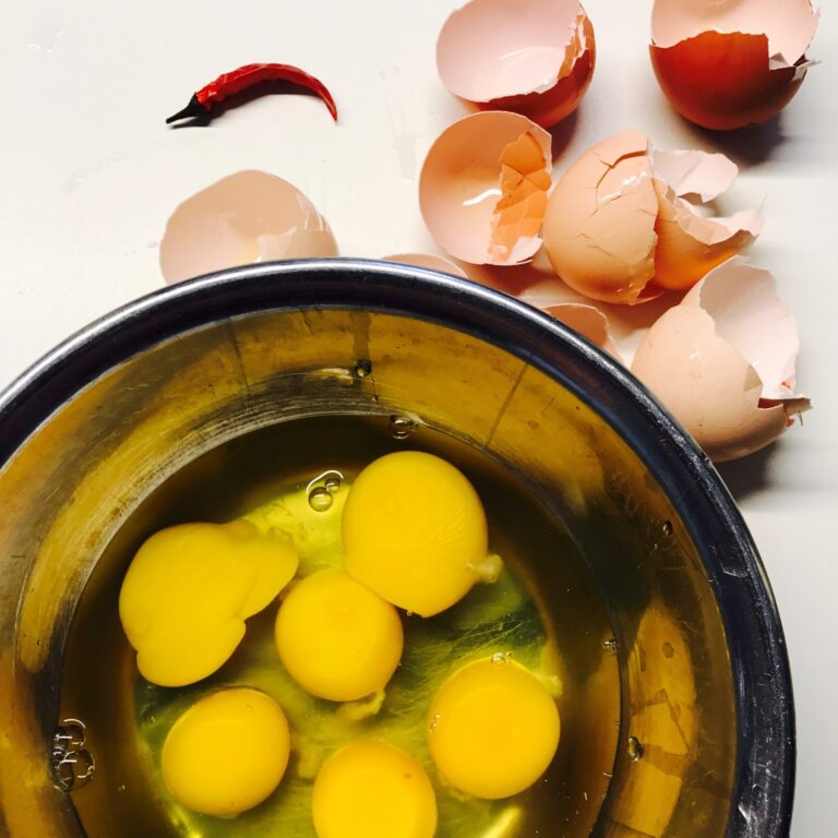 bowl of eggs, with broken shells alongside