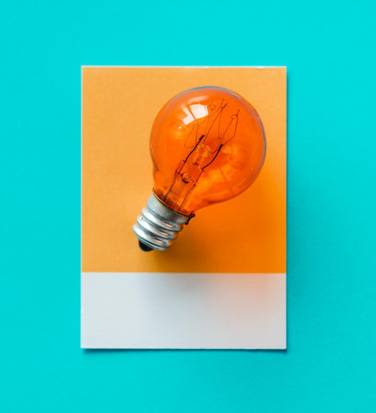 orange lightbulb on orange square with white rectangle, on teal background