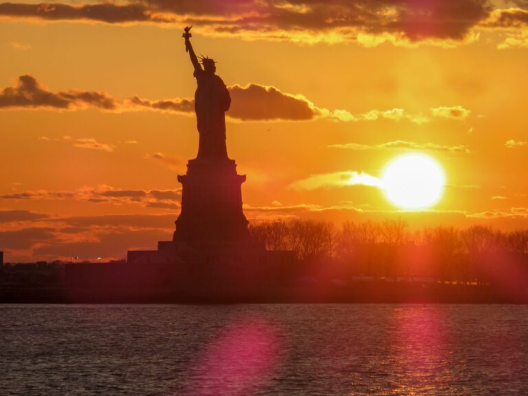 statue of liberty against a setting sun
