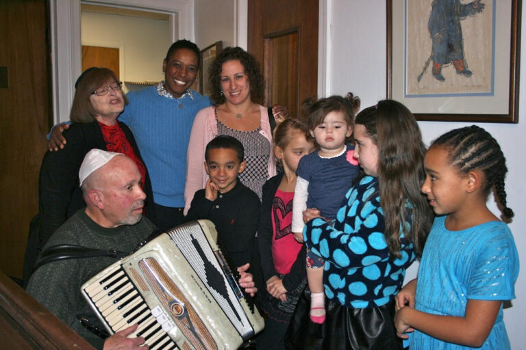 children and adults, including one playing accordian