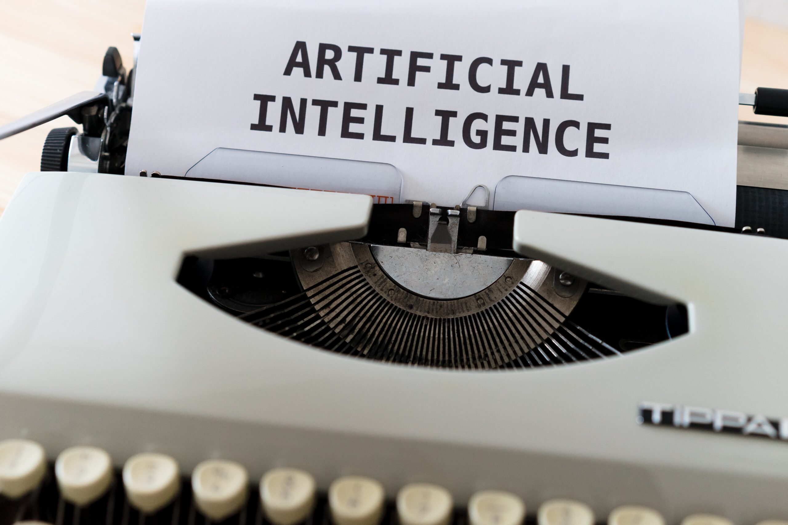 A typewriter with a sheet of paper displaying ARTIFICIAL INTELLIGENCE in uppercase letters.