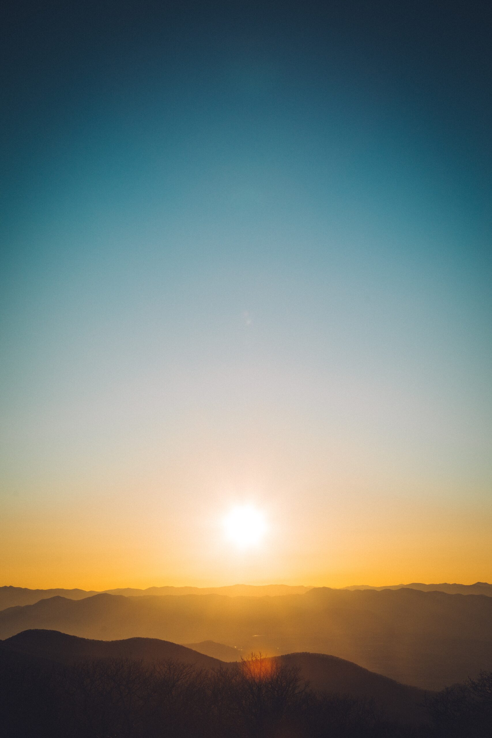 Sunrise over a mountain range with a clear sky and hazy horizon.