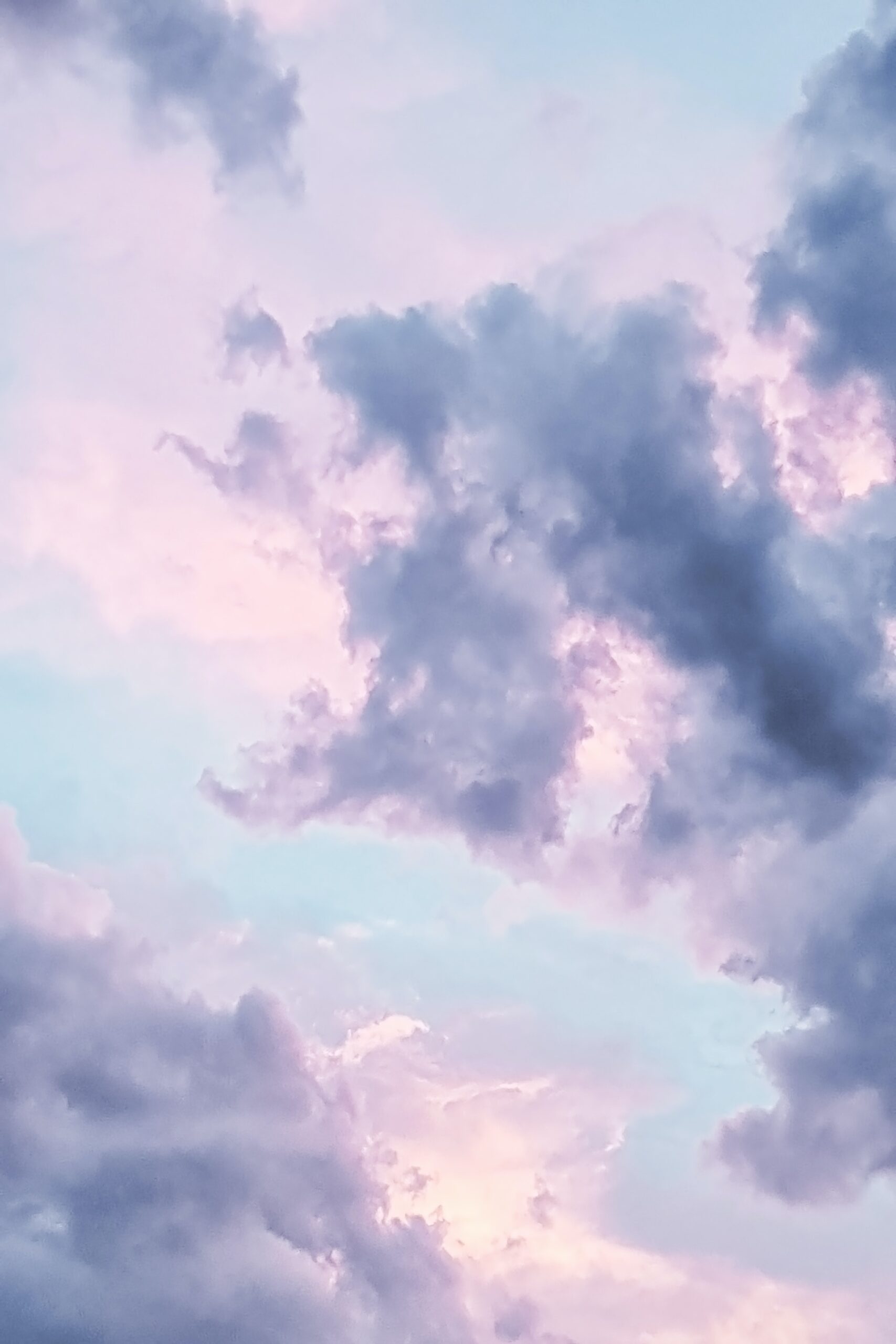 Soft pastel clouds against a blue sky at dawn or dusk, creating a serene and calming atmosphere.