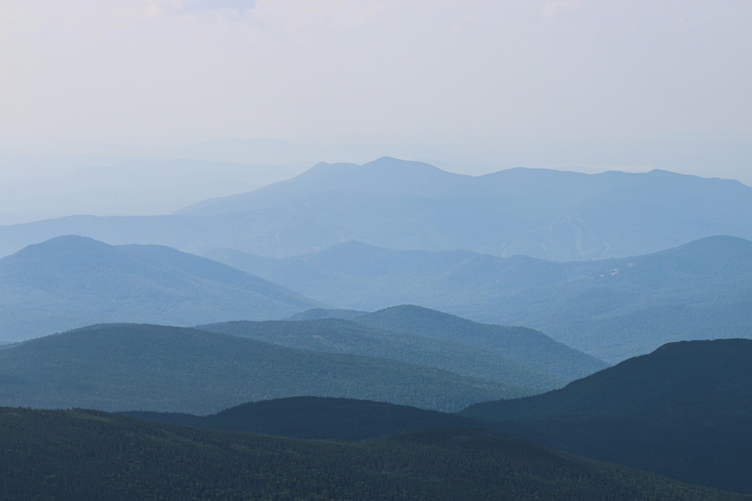 A serene view of layered blue mountain ranges under a hazy sky.