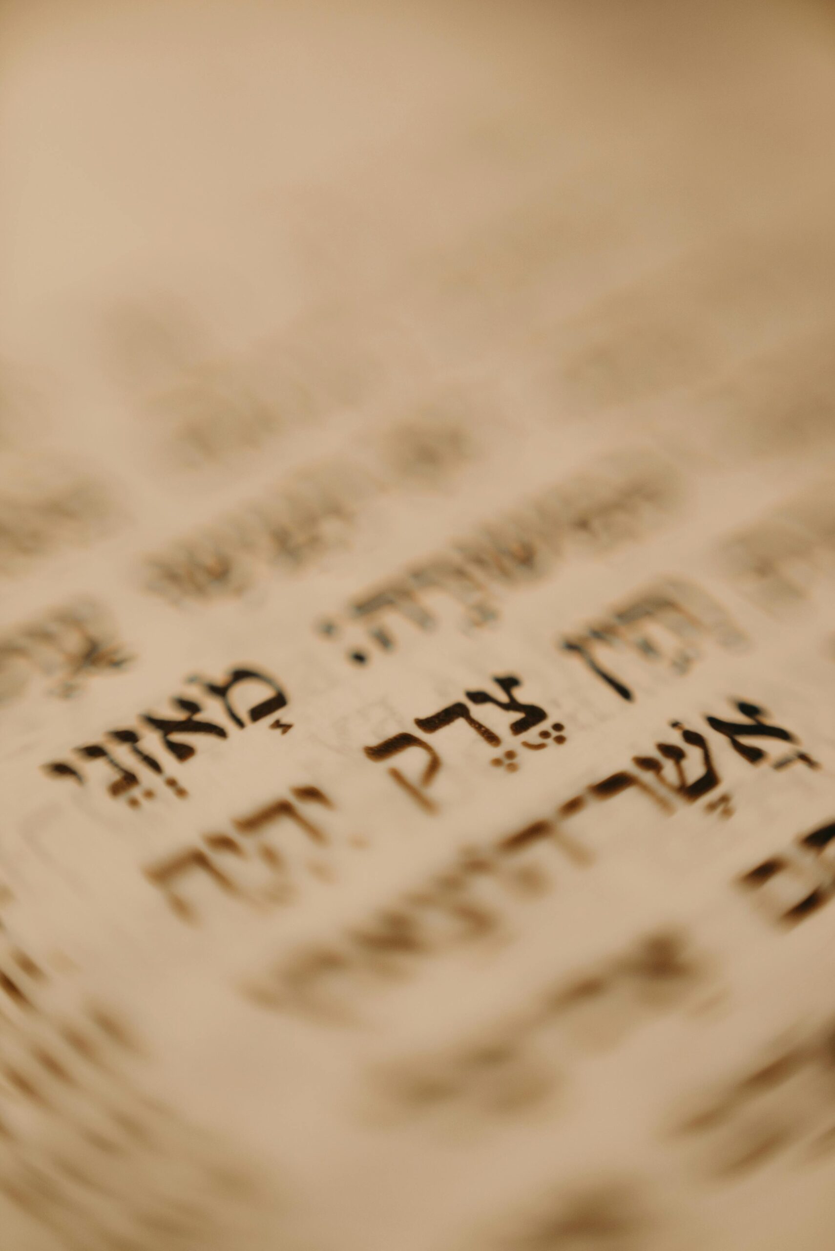 Blurred close-up of Hebrew text on a sepia-toned page.
