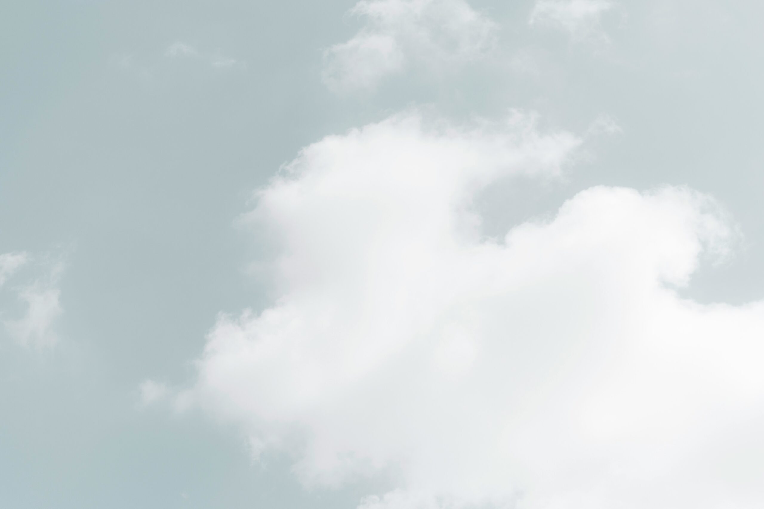 Fluffy white clouds in a pale blue sky.