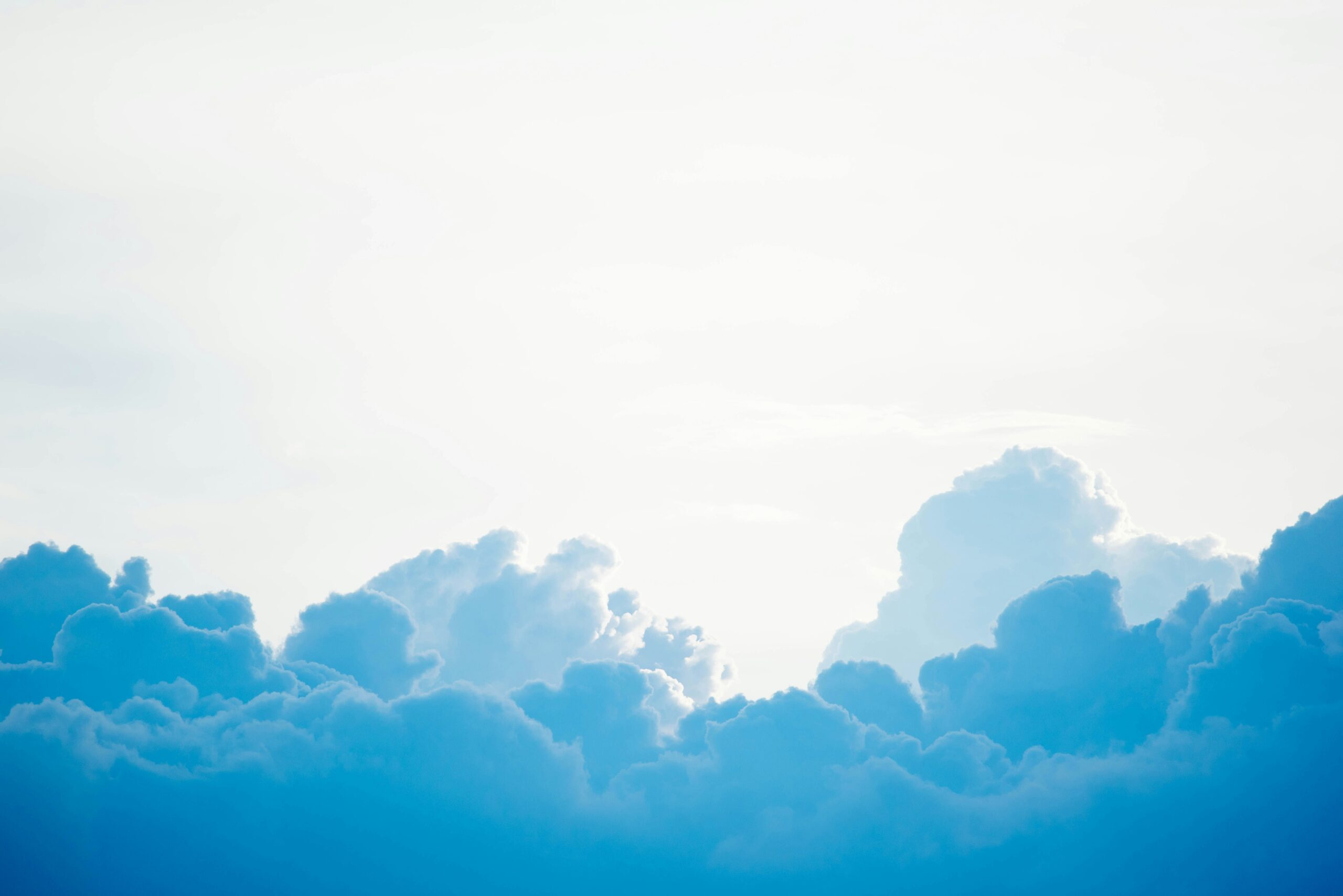 Fluffy blue and white clouds against a bright, sunlit sky.