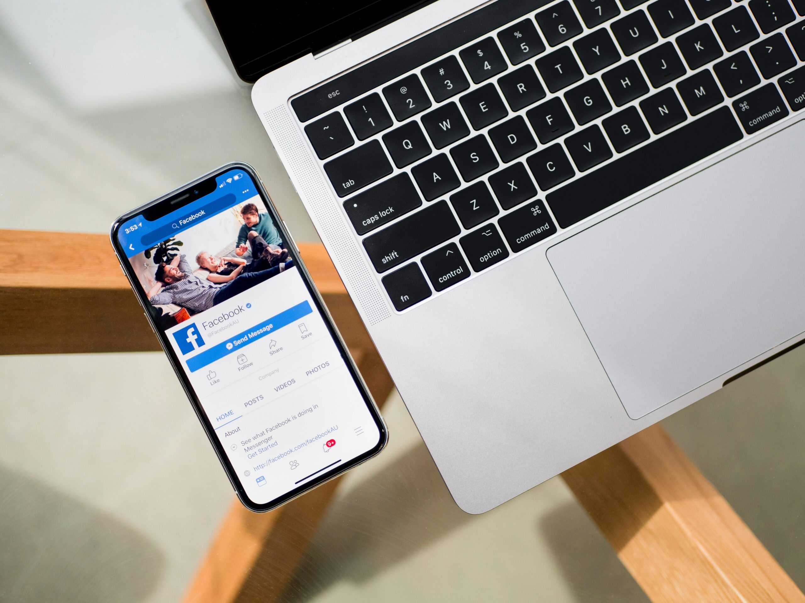 Smartphone displaying Facebook app on a table next to an open laptop.
