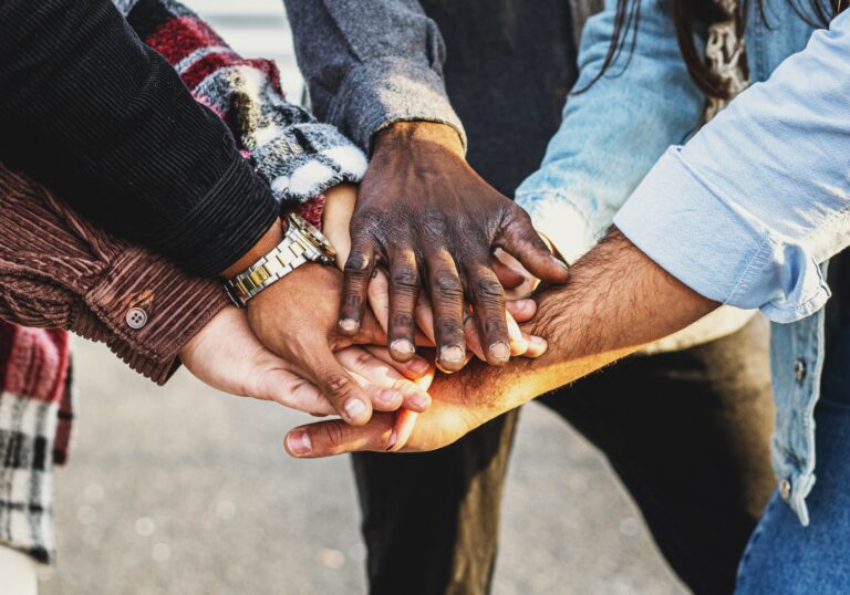 A diverse group of hands stacked together in a show of unity and teamwork.