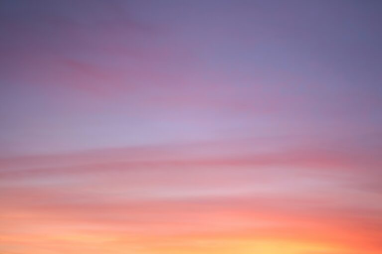 A tranquil sky at sunset, blending soft hues of pink, orange, and purple with gentle, wispy clouds.