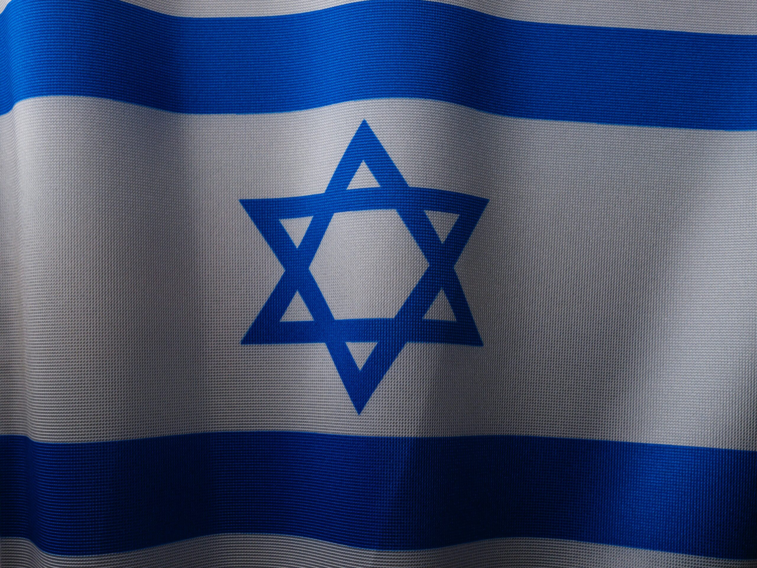 Close-up of the Israeli flag, displaying a blue Star of David between two horizontal blue stripes on a white background.