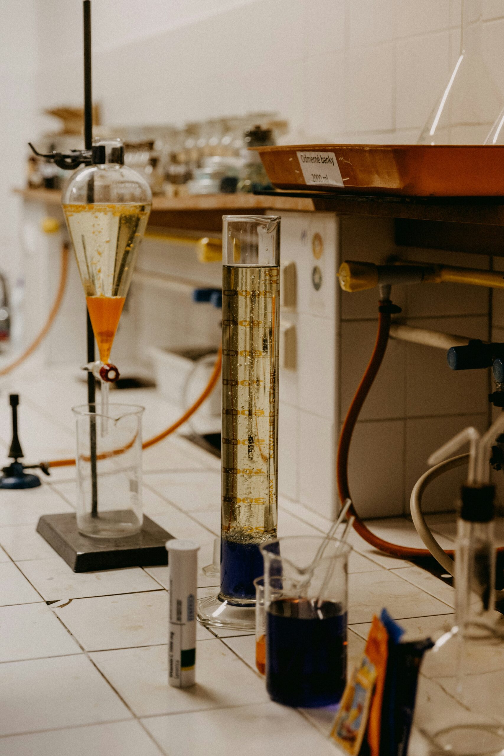 Lab bench with glassware, graduated cylinder, beakers with blue liquid, and chemical apparatus.