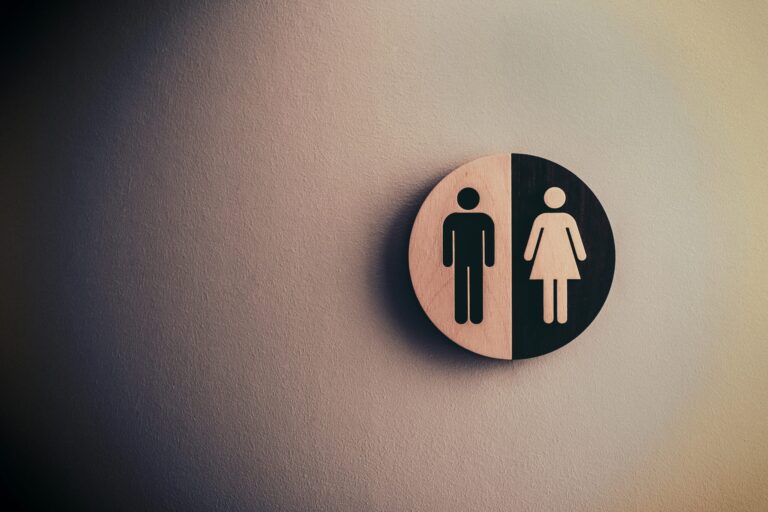 A circular restroom sign showing male and female symbols on a textured wall.
