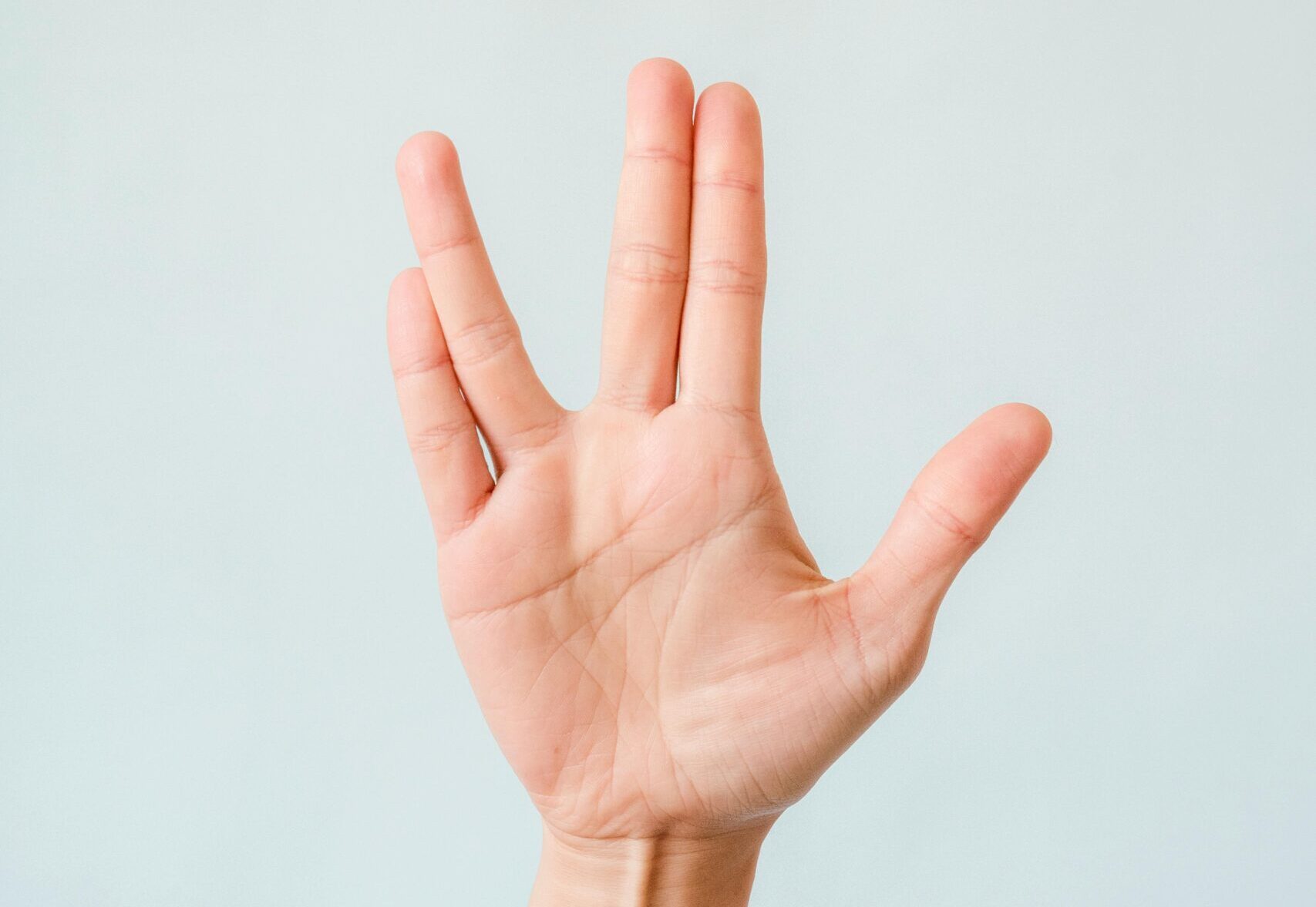 A hand making the Vulcan salute gesture against a plain light background.