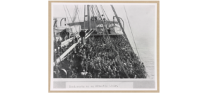 A crowded ship deck filled with immigrants crossing the Atlantic Ocean in the early 1900s.