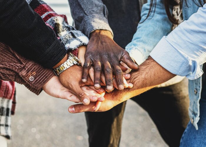 A diverse group of hands stacked together in a show of unity and teamwork.