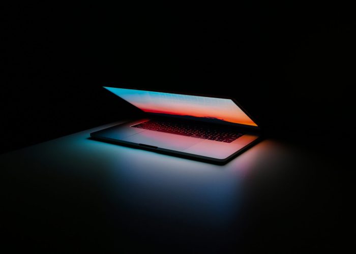 laptop in darkness, with LED light reflecting on keyboard