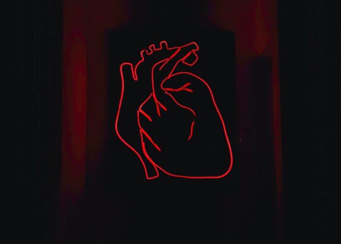Neon red heart outline with dark background.