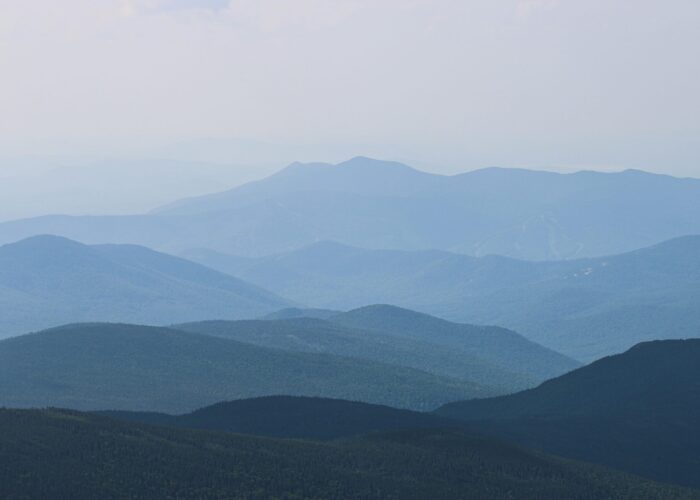 A serene view of layered blue mountain ranges under a hazy sky.