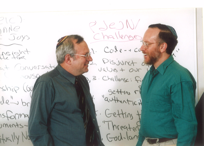 Rabbis Jeffrey Schein and Brian Nevins-Goldman in front of a white board covered with writing