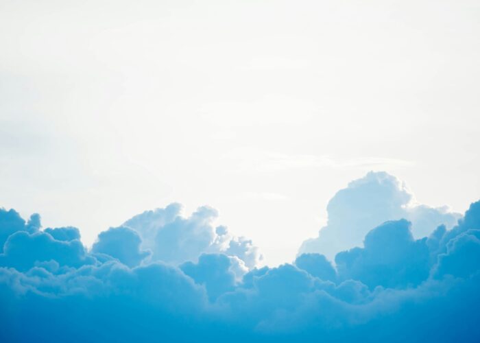 Fluffy blue and white clouds against a bright, sunlit sky.