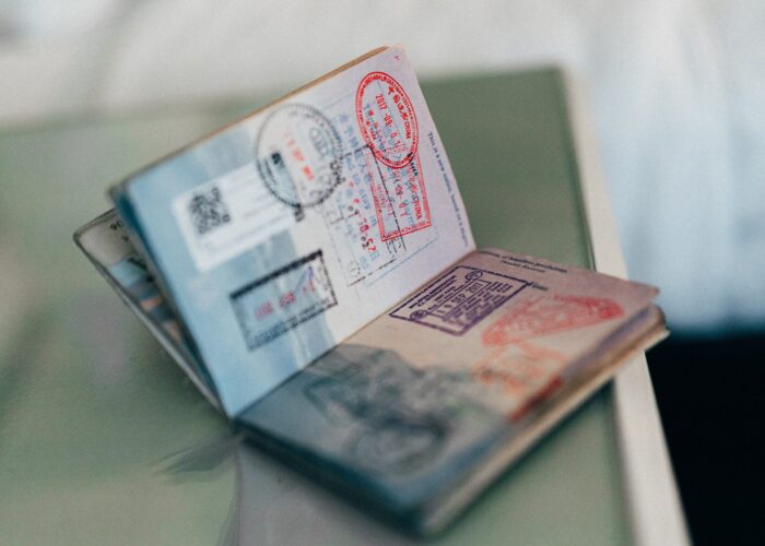 Open passport showing multiple visa stamps and entry-exit stamps on its pages, resting on a reflective surface.