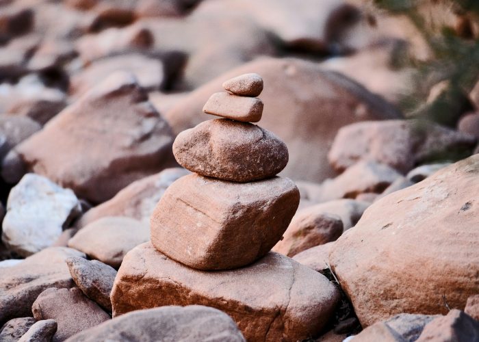 Stacked stones on a rocky surface, forming a balanced cairn in a natural setting.