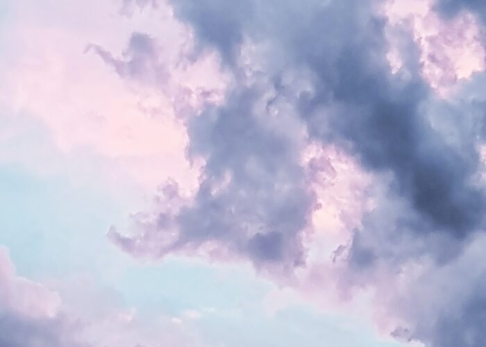 Soft pastel clouds against a blue sky at dawn or dusk, creating a serene and calming atmosphere.