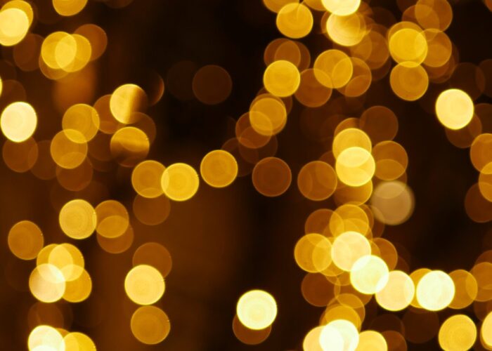 Golden bokeh lights create a warm, festive atmosphere with blurred circles against a dark background.
