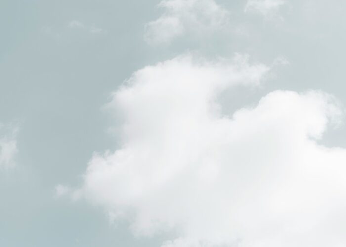 Fluffy white clouds in a pale blue sky.