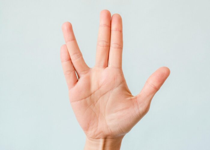 A hand making the Vulcan salute gesture against a plain light background.
