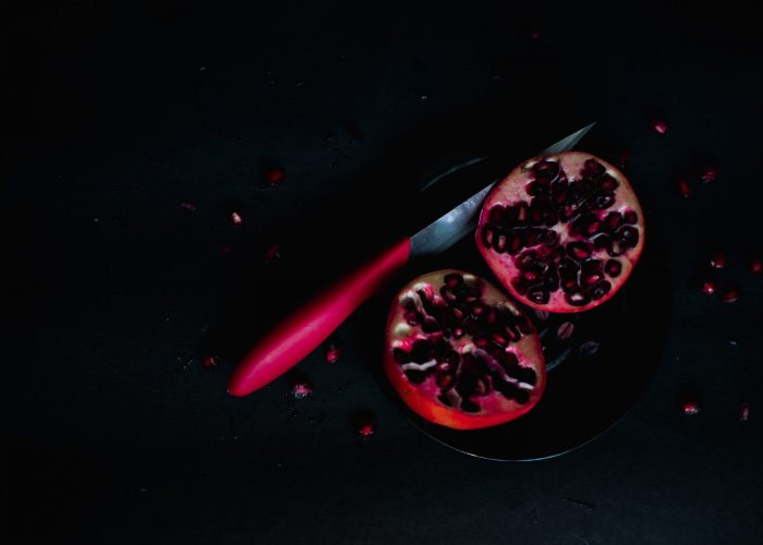 cut pomegranate and pink knife in darkness