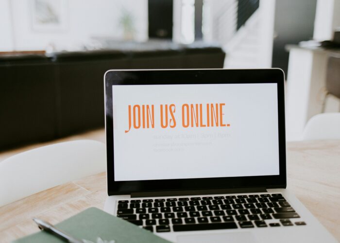 Laptop on a table with Join us online on the screen.