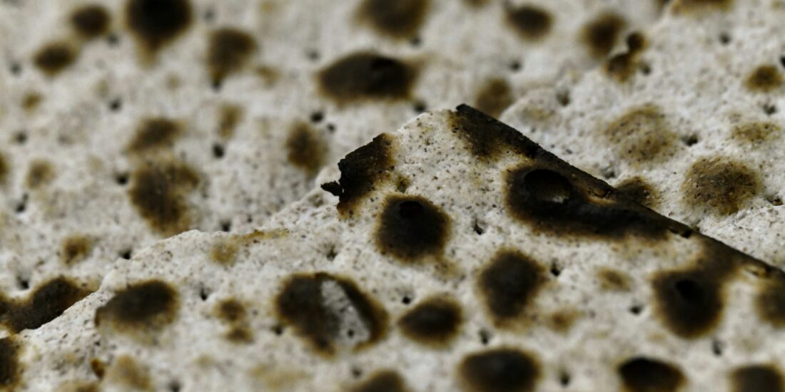 Close-up of pieces of matzah bread, showing its crisp, dotted, and slightly burnt surface.