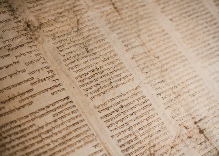 Close-up of an ancient, weathered manuscript with Hebrew text arranged in vertical columns.