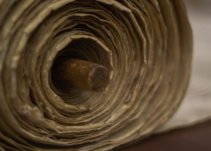 Close-up of an ancient rolled scroll with a wooden spindle in the center.