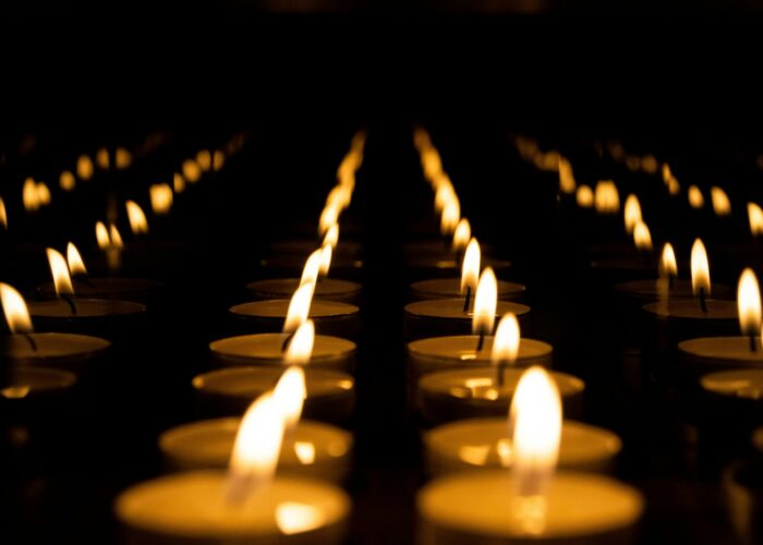 Rows of lit candles creating a warm, glowing ambiance in a dark setting.