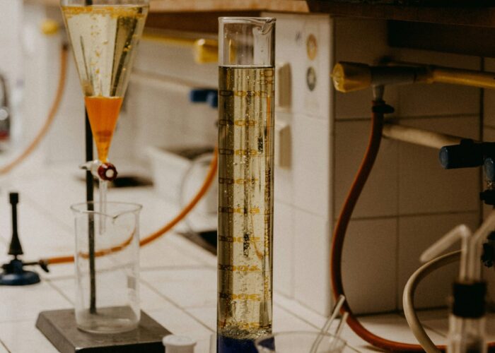 Lab bench with glassware, graduated cylinder, beakers with blue liquid, and chemical apparatus.