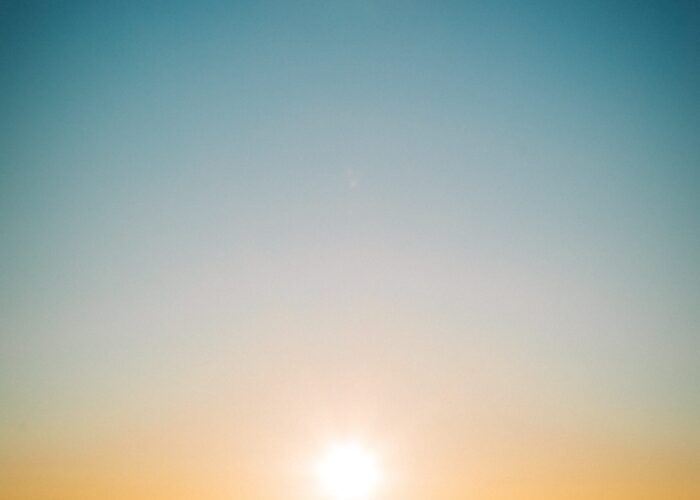 Sunrise over a mountain range with a clear sky and hazy horizon.